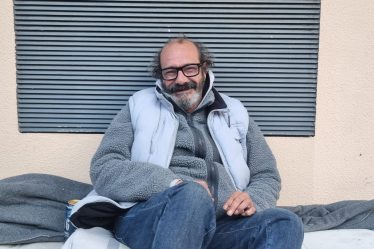 Jean-Raphaël, 54 ans, sans-abri assis sur son matelas dans une rue de Lyon.